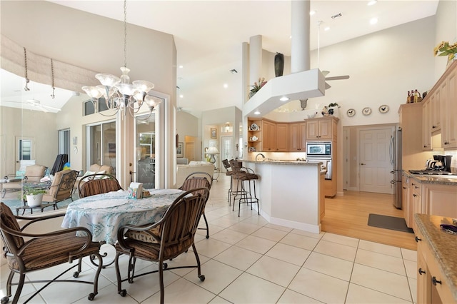 dining area featuring light tile floors, a notable chandelier, and high vaulted ceiling