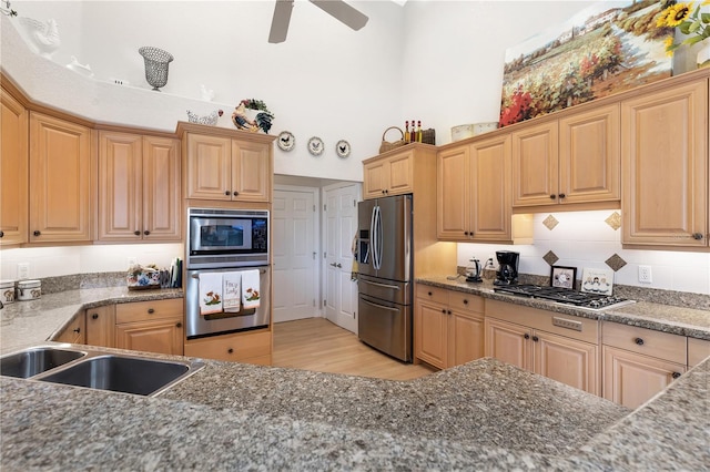 kitchen featuring backsplash, stainless steel appliances, light wood-type flooring, ceiling fan, and sink