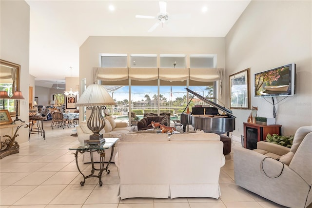 tiled living room featuring a towering ceiling and ceiling fan with notable chandelier