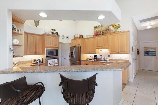 kitchen featuring light brown cabinetry, kitchen peninsula, stainless steel appliances, and light tile floors