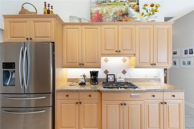 kitchen with backsplash, light brown cabinetry, stainless steel appliances, and light stone counters