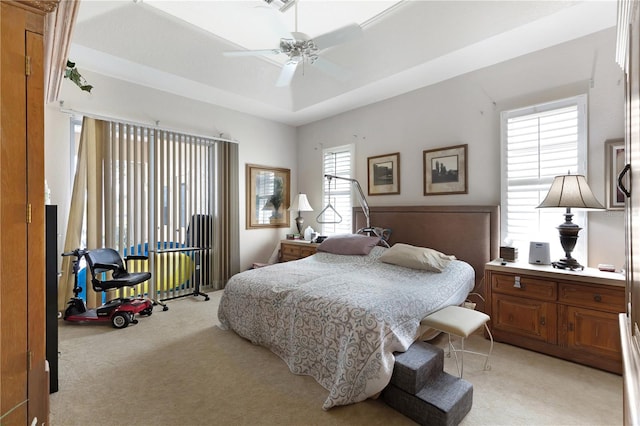 bedroom with light carpet, a raised ceiling, and ceiling fan