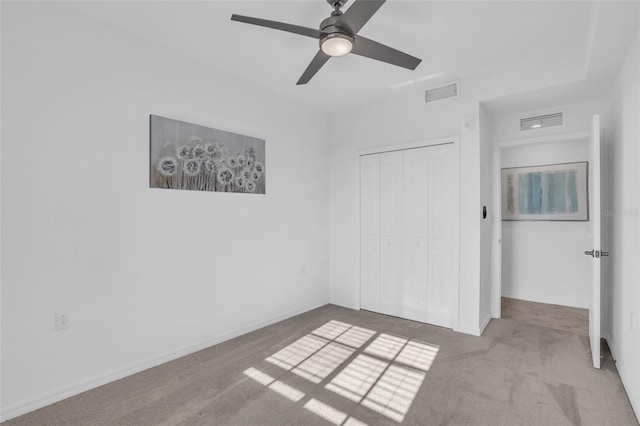 unfurnished bedroom featuring light colored carpet, ceiling fan, and a closet