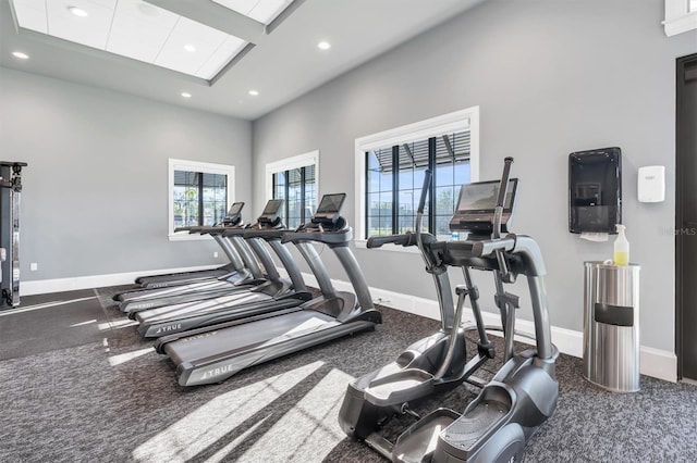 exercise room with a towering ceiling and dark colored carpet