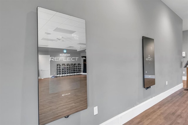 hallway with light hardwood / wood-style floors and a paneled ceiling