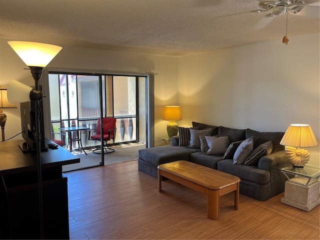 living room featuring ceiling fan, a textured ceiling, and wood finished floors