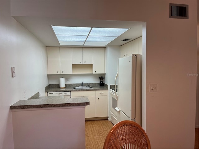 kitchen featuring sink, white cabinets, light hardwood / wood-style floors, and white appliances