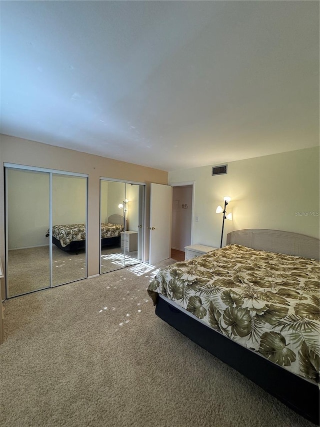 carpeted bedroom with visible vents and multiple closets