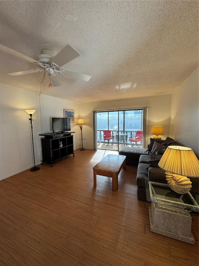 living room with ceiling fan, a textured ceiling, and wood finished floors