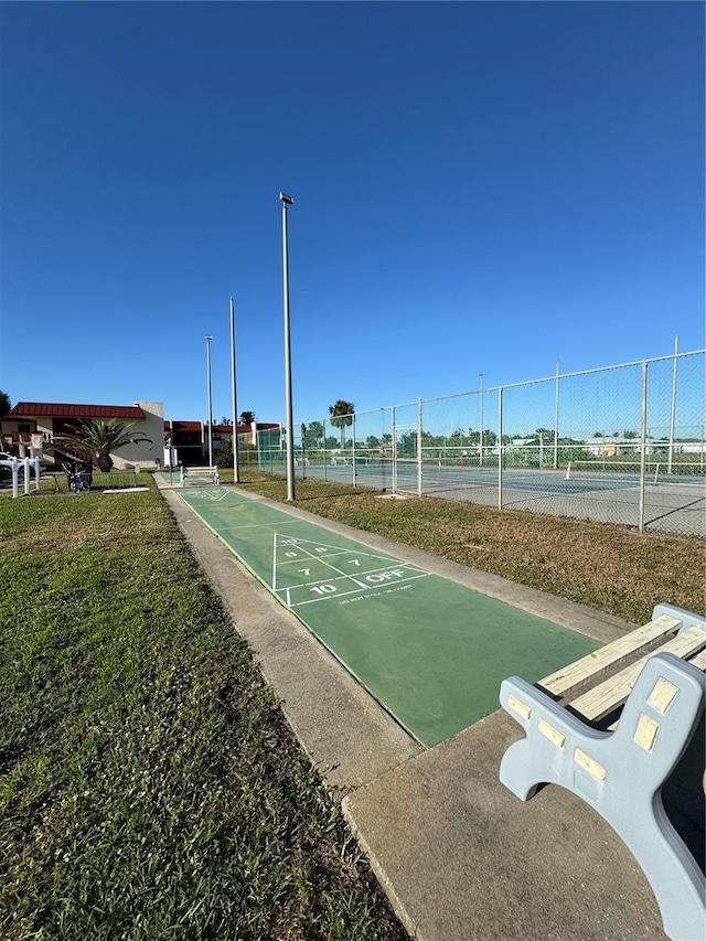 view of community with a tennis court, fence, and shuffleboard