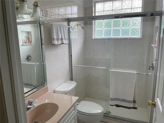 bathroom featuring vanity, toilet, tile walls, and a shower with door