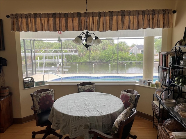 dining room featuring a chandelier, a water view, and light hardwood / wood-style flooring