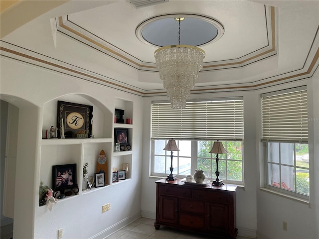 room details with a tray ceiling, built in features, ornamental molding, and a chandelier