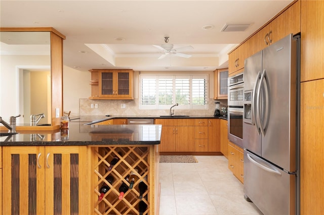 kitchen with crown molding, appliances with stainless steel finishes, sink, kitchen peninsula, and a tray ceiling