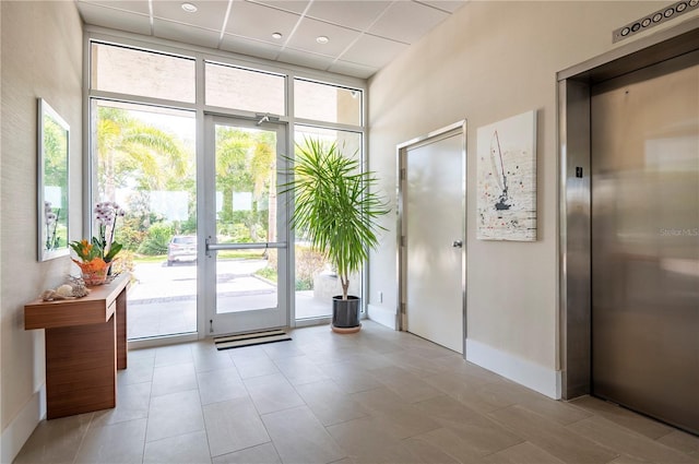 entryway with elevator, a towering ceiling, and expansive windows