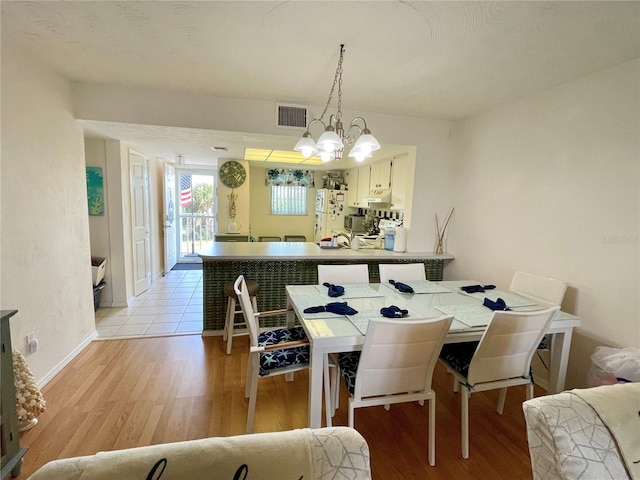 dining space with light hardwood / wood-style flooring and a chandelier