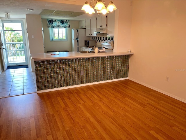 kitchen with pendant lighting, stainless steel appliances, light hardwood / wood-style floors, white cabinets, and a chandelier