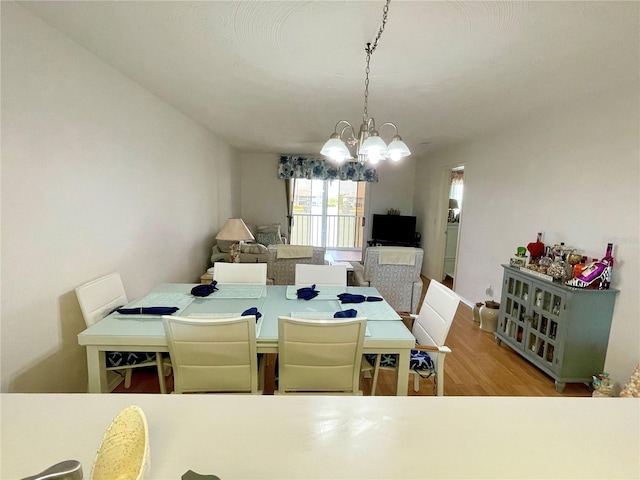 dining area with light hardwood / wood-style flooring and a notable chandelier