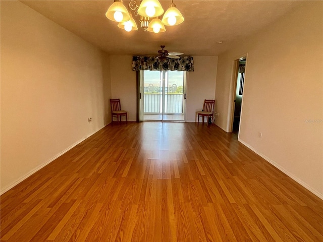 spare room with hardwood / wood-style flooring and ceiling fan with notable chandelier