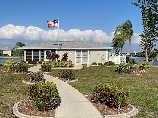 view of front of home with a water view, a sunroom, and a front yard
