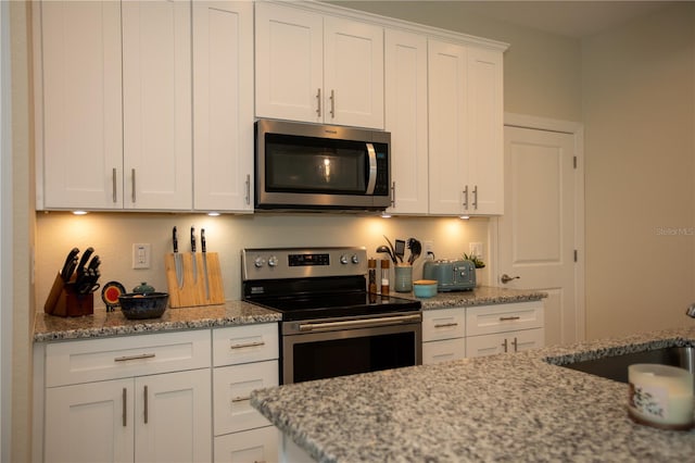 kitchen featuring stainless steel appliances, white cabinets, sink, and light stone countertops