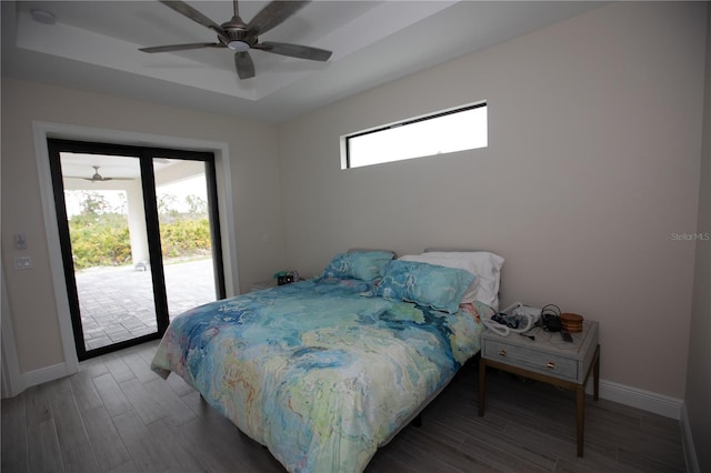 bedroom featuring dark hardwood / wood-style flooring, ceiling fan, access to exterior, and multiple windows