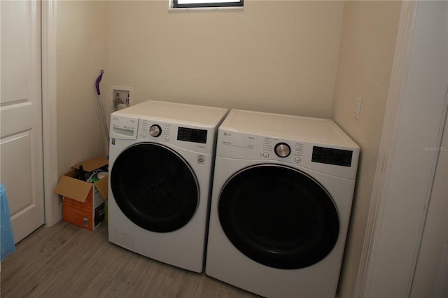 laundry room with hookup for a washing machine, separate washer and dryer, and light wood-type flooring