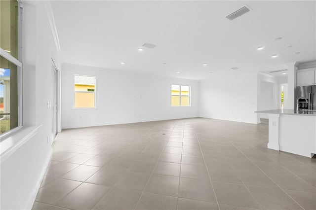 unfurnished living room with crown molding and light tile patterned floors