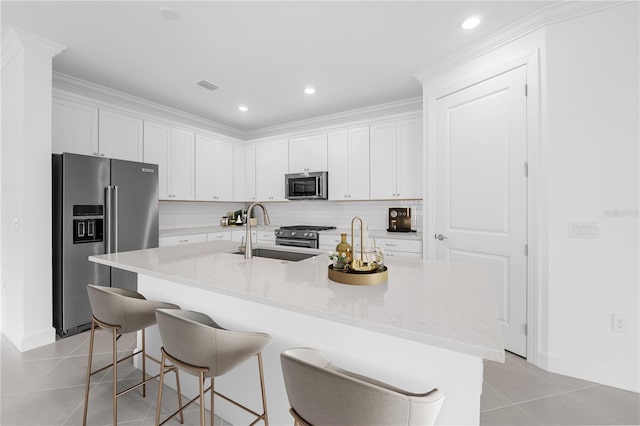 kitchen with appliances with stainless steel finishes, white cabinetry, sink, and a center island with sink