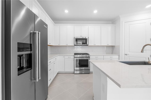 kitchen with light stone counters, stainless steel appliances, light tile patterned floors, white cabinets, and sink