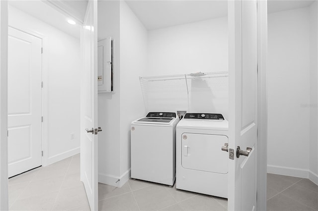 clothes washing area featuring electric panel, washer and clothes dryer, and light tile patterned flooring