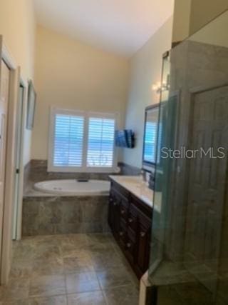 bathroom with shower with separate bathtub, vanity, vaulted ceiling, and tile patterned flooring