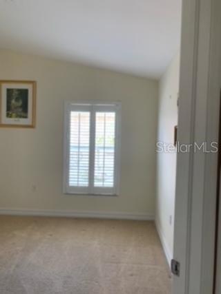 carpeted spare room with vaulted ceiling