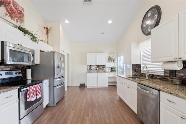 kitchen with dark wood-type flooring, white cabinets, decorative backsplash, sink, and appliances with stainless steel finishes