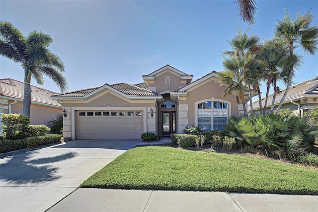 mediterranean / spanish home featuring a garage and a front lawn