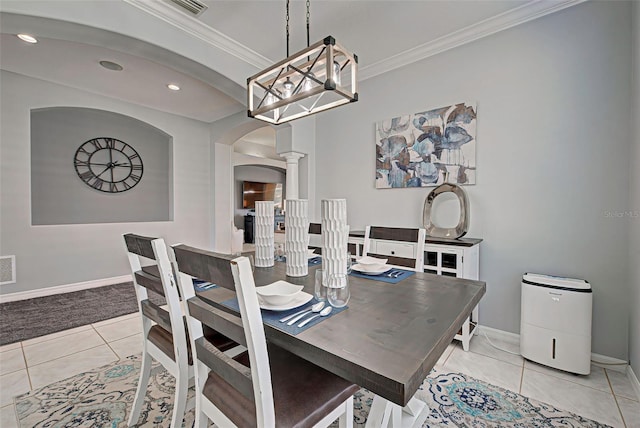 tiled dining space featuring crown molding and decorative columns