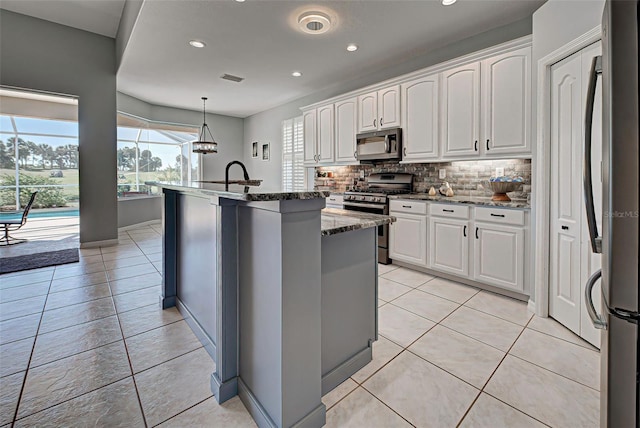 kitchen with decorative light fixtures, appliances with stainless steel finishes, backsplash, light tile flooring, and white cabinets