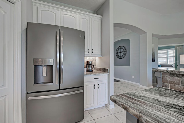 kitchen featuring light stone counters, light tile flooring, stainless steel fridge with ice dispenser, and white cabinetry