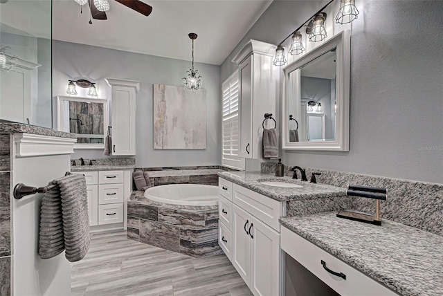 bathroom with double sink, a relaxing tiled bath, oversized vanity, and ceiling fan