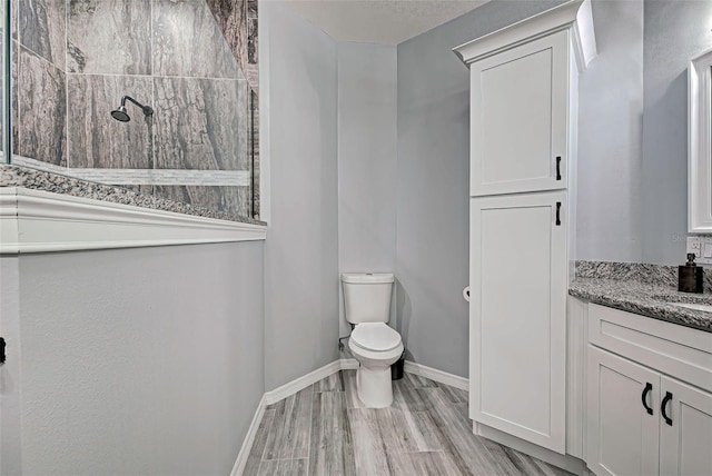 bathroom featuring vanity, a tile shower, and toilet