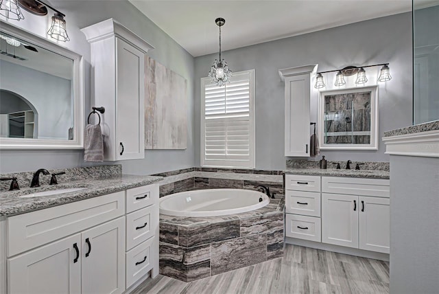 bathroom featuring a relaxing tiled bath and vanity