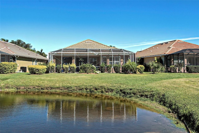 back of property featuring glass enclosure, a lawn, and a water view