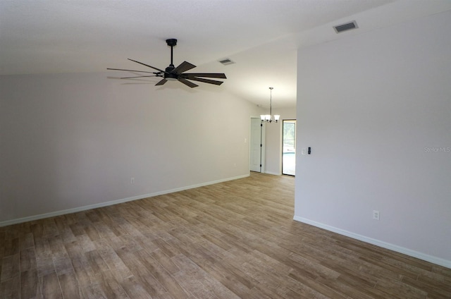 spare room featuring hardwood / wood-style flooring, ceiling fan with notable chandelier, and lofted ceiling