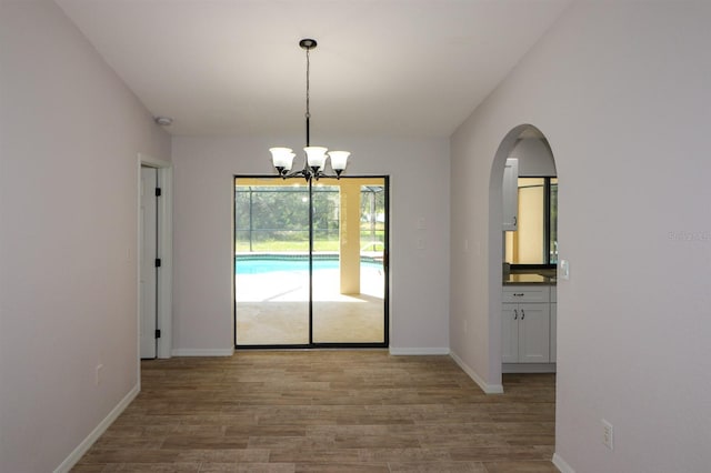 unfurnished dining area featuring hardwood / wood-style floors and an inviting chandelier