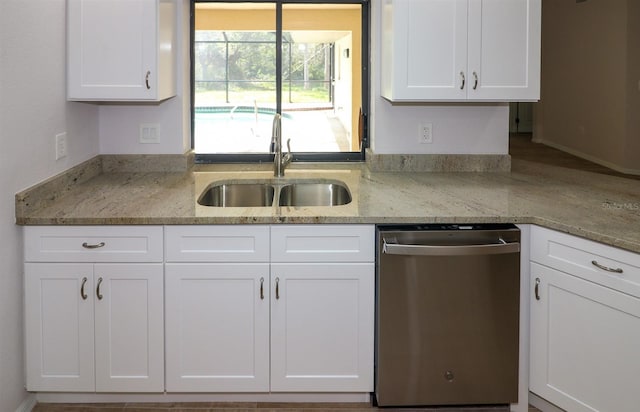 kitchen with stainless steel dishwasher, sink, and white cabinetry