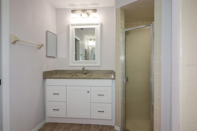 bathroom with vanity with extensive cabinet space, an enclosed shower, and hardwood / wood-style flooring