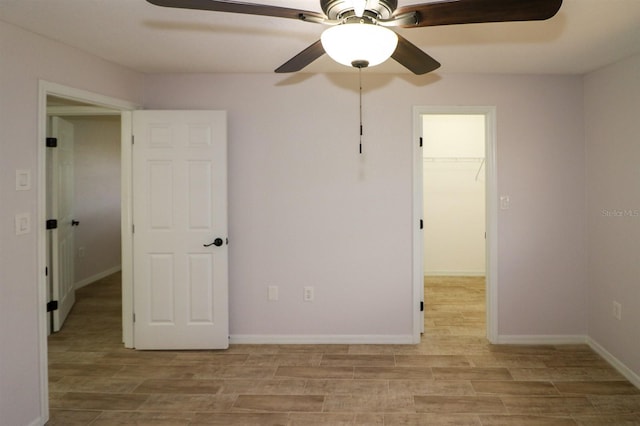 unfurnished bedroom featuring a closet, a spacious closet, and ceiling fan