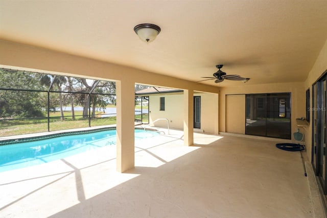 view of swimming pool featuring glass enclosure, ceiling fan, and a patio area