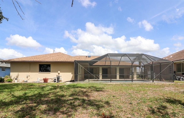 back of house with glass enclosure and a lawn