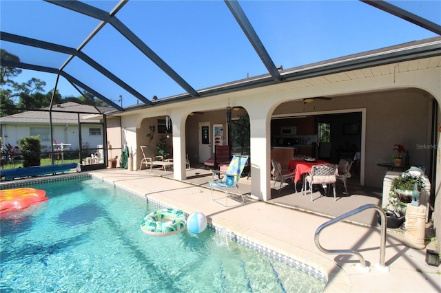 view of swimming pool featuring a patio area, ceiling fan, and glass enclosure